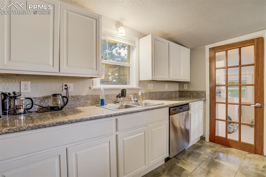 Image 8 of 24: Kitchen featuring stainless steel dishwasher, a textured ceiling, white cab