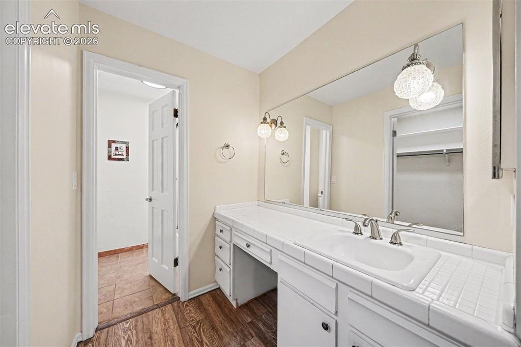 Image 16 of 42: Bathroom vanity featuring a tiled countertop with an integrated sink, brush