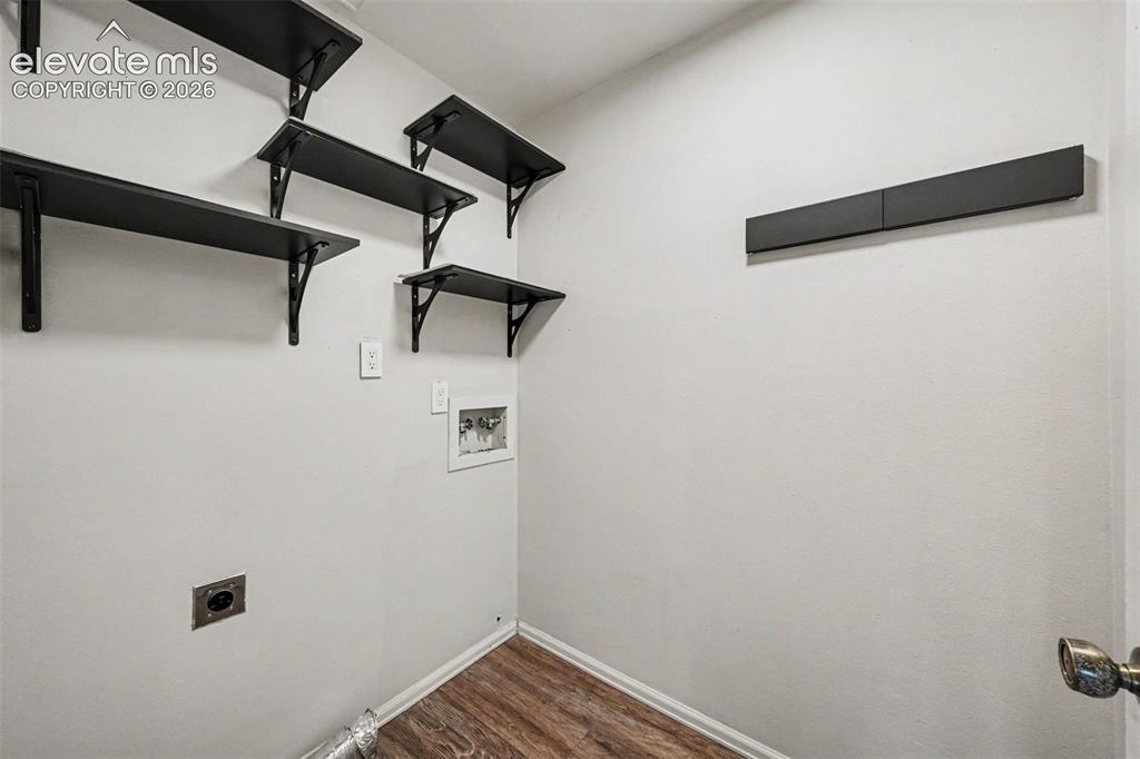 Image 21 of 42: Laundry room featuring a wood-finish floor, multiple wall-mounted shelves,