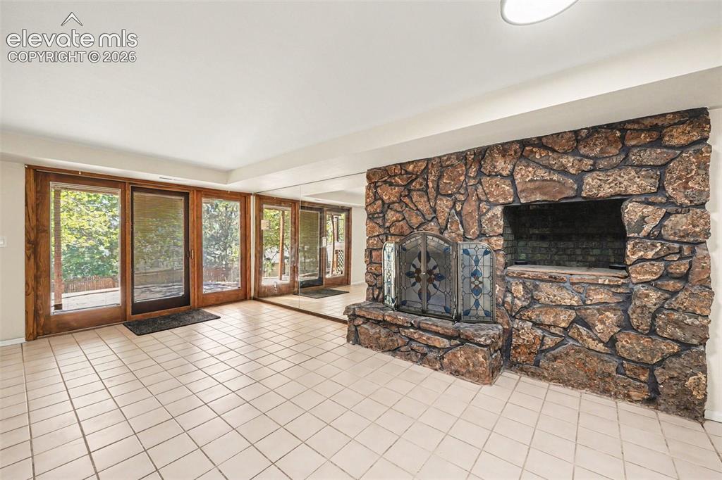 Image 23 of 42: Spacious room featuring a prominent stone fireplace with an integrated hear