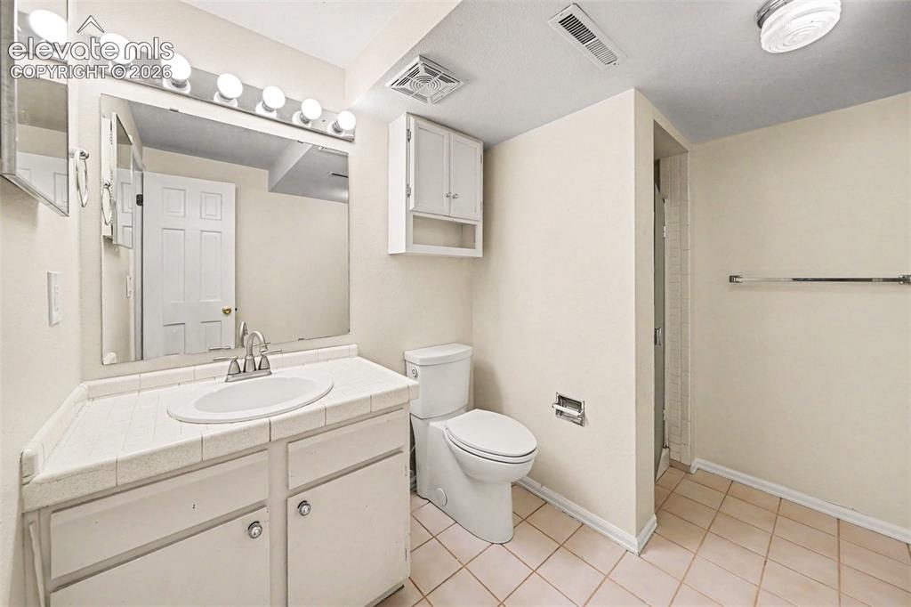 Image 27 of 42: Bathroom featuring a white vanity with an integrated sink and tile countert