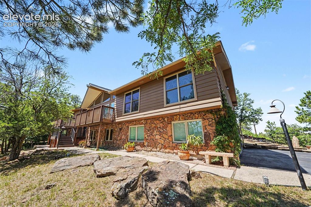 Image 3 of 42: Multi-level exterior featuring a stone facade and horizontal siding
