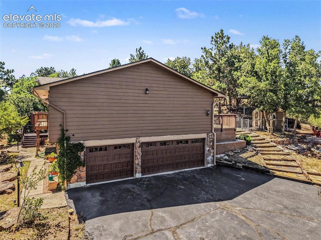 Image 30 of 42: Exterior featuring a three-car garage with stone accents, a wood-sided uppe