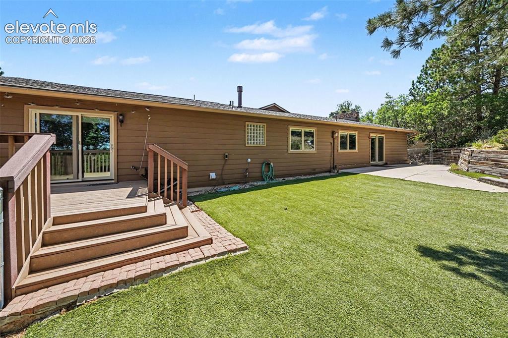 Image 36 of 42: Expansive artificial turf lawn with a composite deck featuring railings and