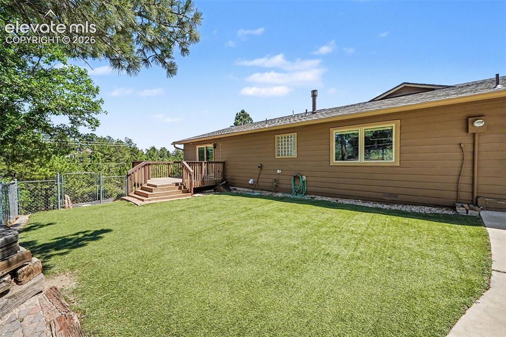 Image 37 of 42: Expansive artificial turf lawn with a multi-level composite deck and chain