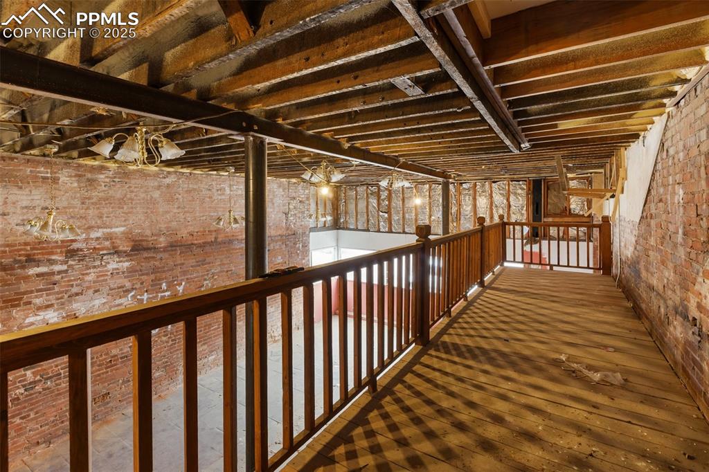 Image 10 of 34: Expansive storefront interior with exposed brick, tall ceilings, and loft/m
