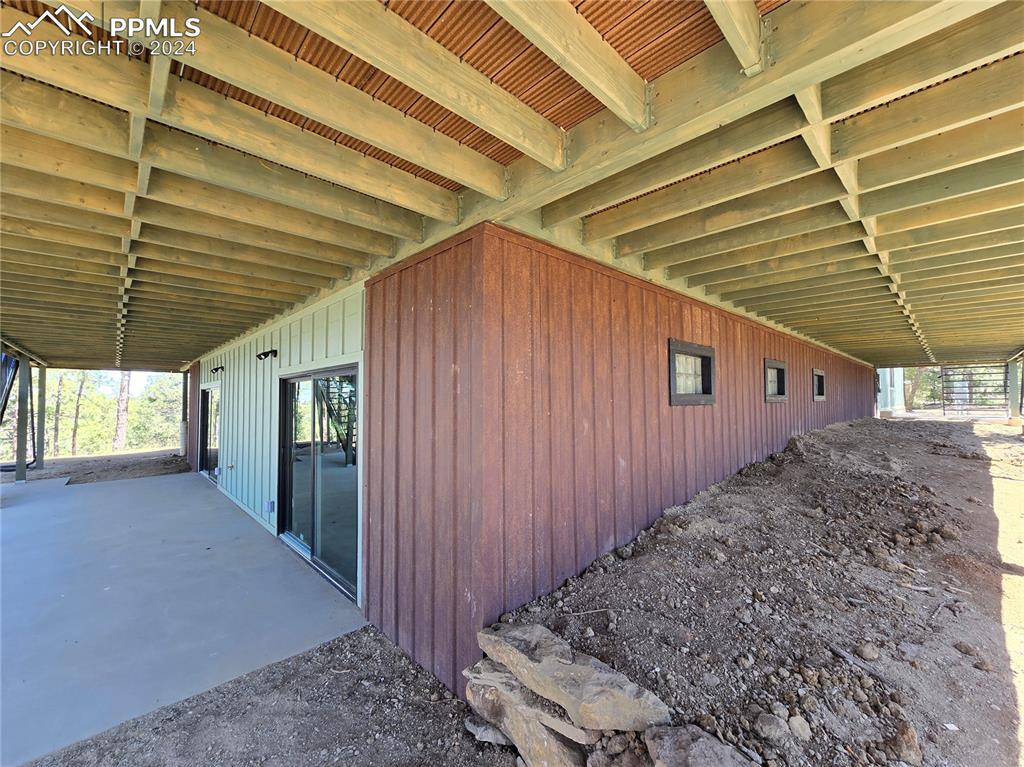 Image 12 of 50: View of lower level patiowith rusted steel siding over ICF foundation.