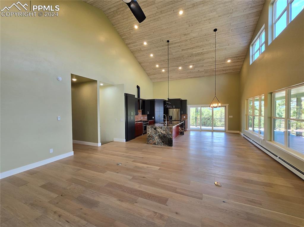 Image 16 of 50: Living room featuring high vaulted ceiling, open kitchen/dining, and light
