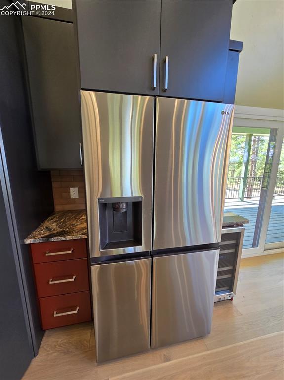 Image 22 of 50: Kitchen with dark stone countertops, stainless steel refrigerator with ice