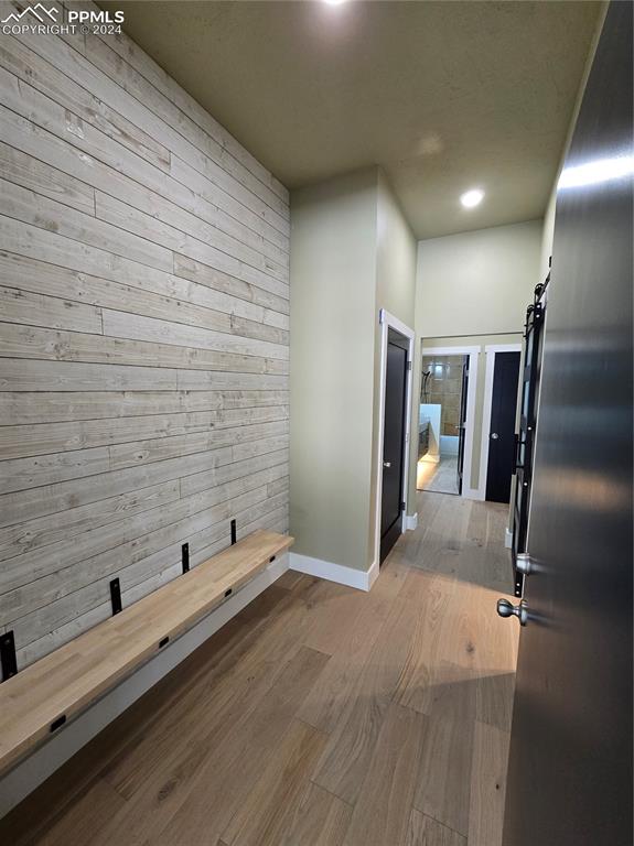 Image 25 of 50: Corridor with light wood-type flooring, a barn door into laundry, and woode