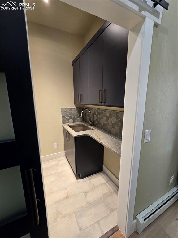 Image 26 of 50: Laundry room featuring a baseboard heating unit, sink, and decorative backs