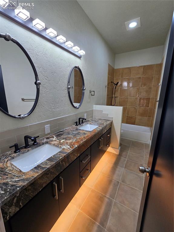 Image 28 of 50: Bathroom featuring tile patterned flooring, vanity, tiled shower / bath com