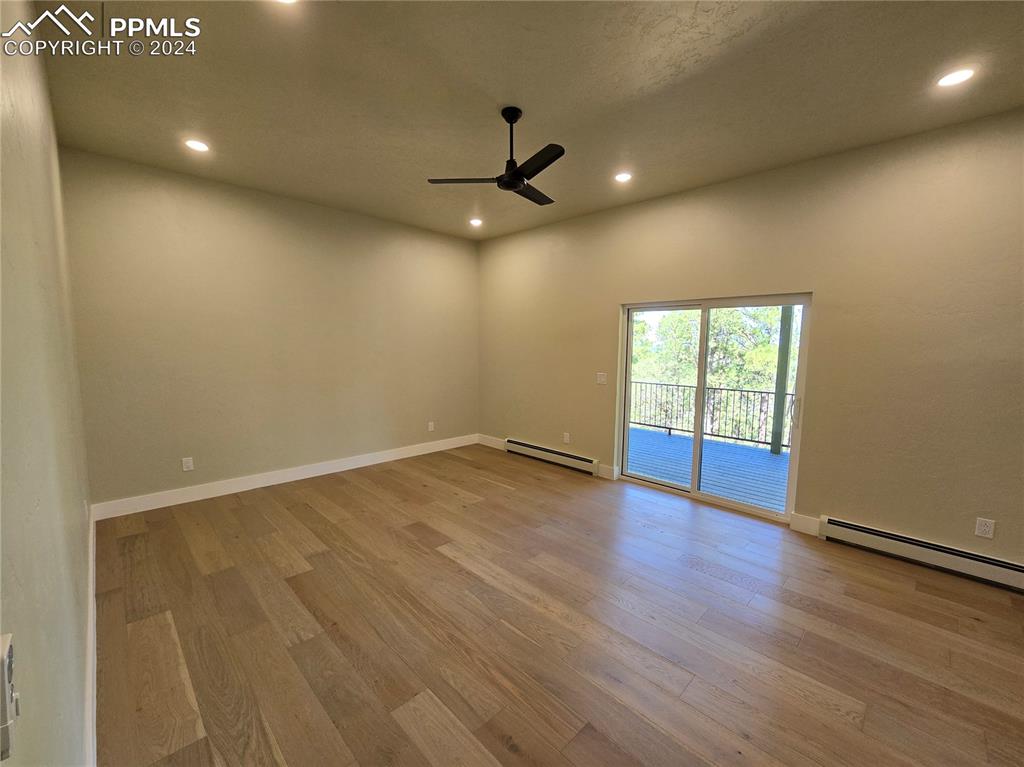 Image 33 of 50: Primary bedroom with a textured ceiling, baseboard heating, ceiling fan, an