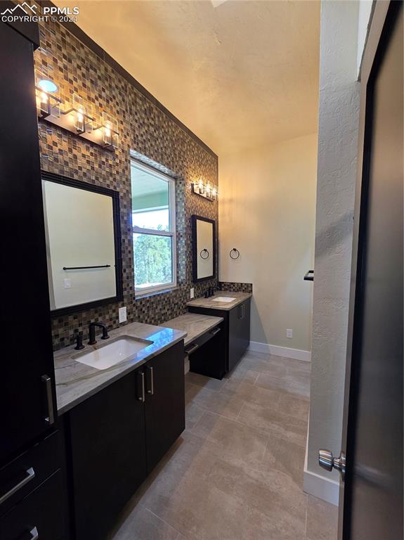 Image 35 of 50: Bathroom with ornamental molding, vanity, and tasteful backsplash