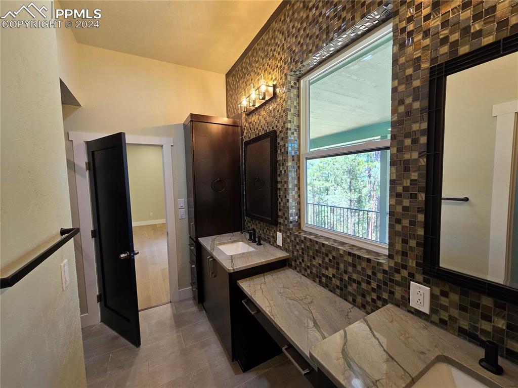 Image 36 of 50: Bathroom with tile patterned flooring, vanity, and tasteful backsplash