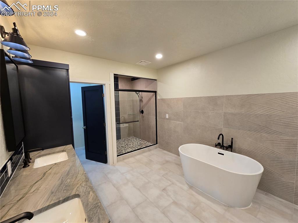 Image 41 of 50: Lower level bathroom with tile walls, independent shower and soaking tub, a