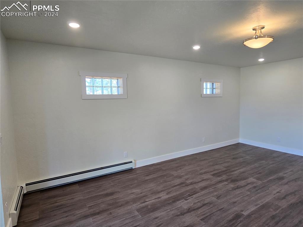 Image 44 of 50: Basement featuring a baseboard radiator and dark hardwood / wood-style floo