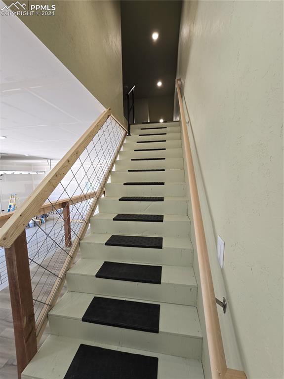 Image 46 of 50: Garage stairway featuring hardwood / wood-style flooring