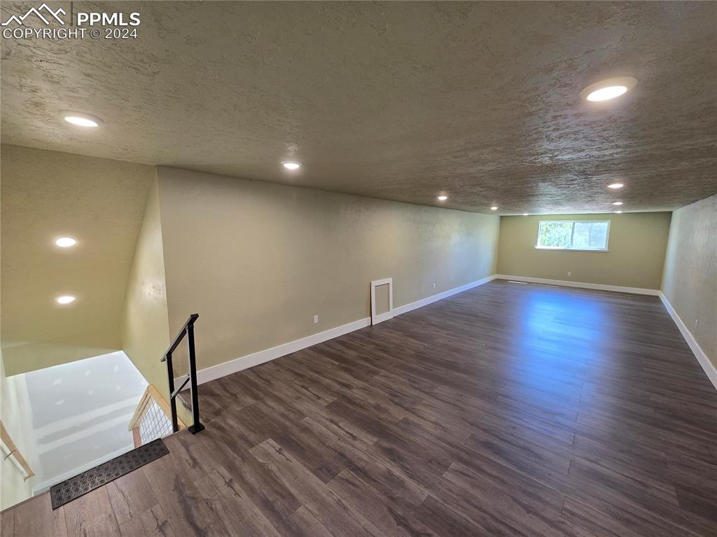 Image 47 of 50: Loft/bonus room featuring a textured ceiling and dark hardwood / wood-style