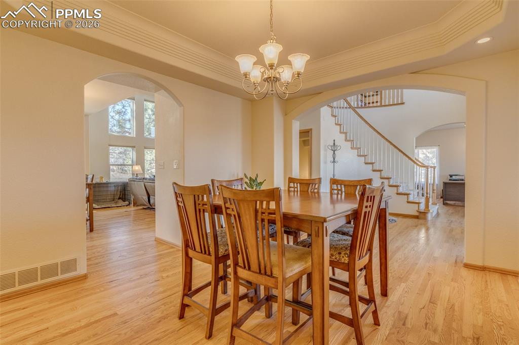 Image 11 of 48: Dining area featuring light wood finished floors, hanging lights, a tray ce