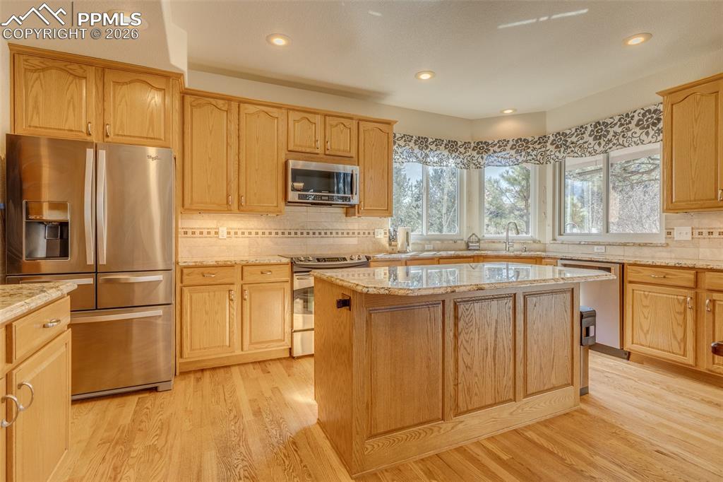 Image 12 of 48: Kitchen with stainless steel appliances, light wood finished floors, decora