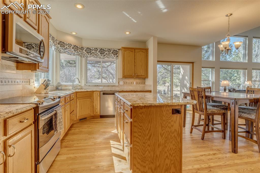 Image 13 of 48: Kitchen with stainless steel appliances, backsplash, a kitchen island, ligh