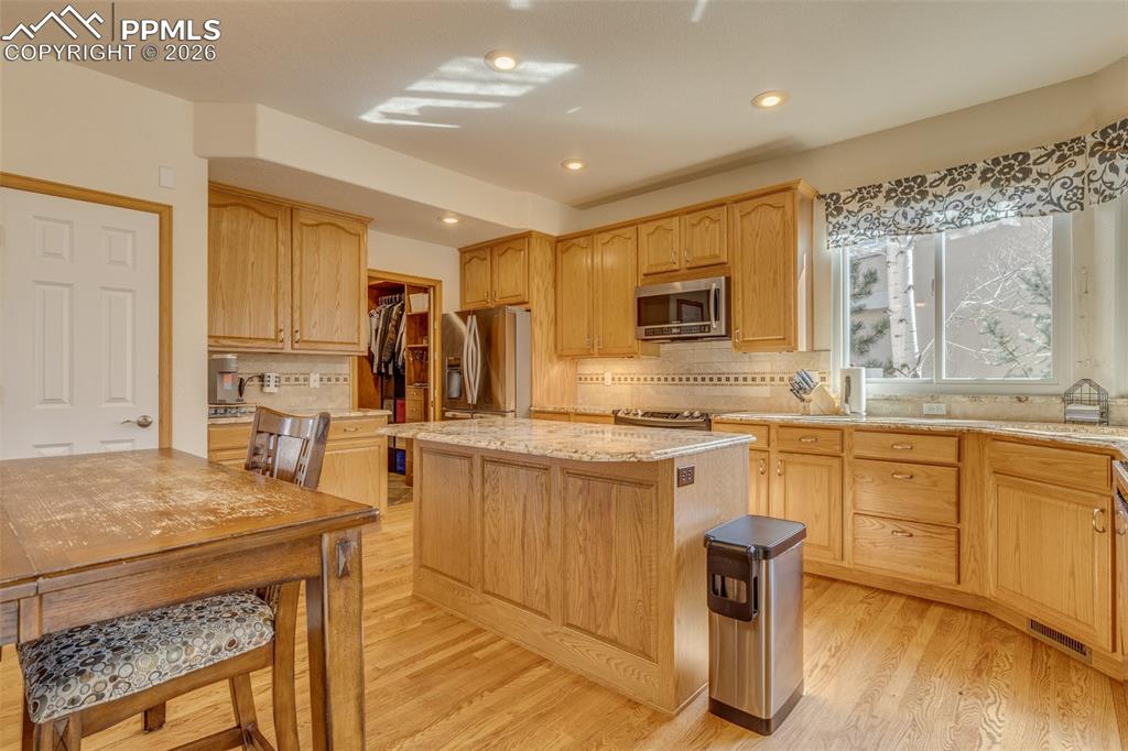 Image 16 of 48: Kitchen with a kitchen island, light stone counters, stainless steel applia