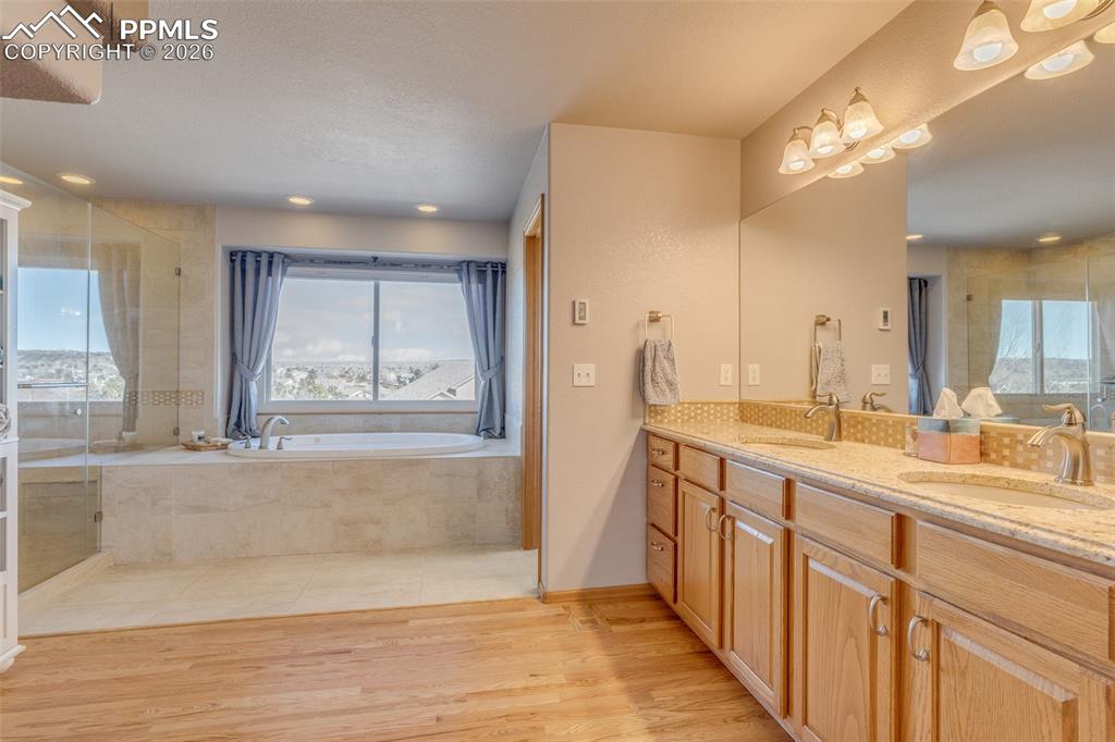 Image 29 of 48: Full bathroom with double vanity, a shower stall, a bath, light wood finish