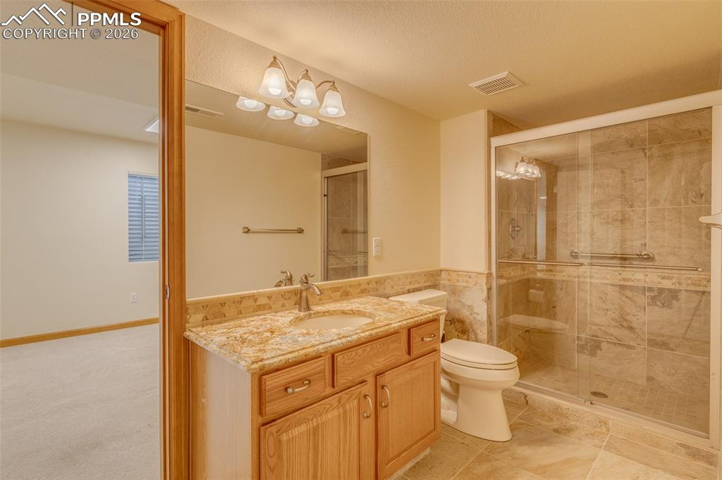 Image 41 of 48: Bathroom with vanity, a shower stall, tile walls, and a textured ceiling