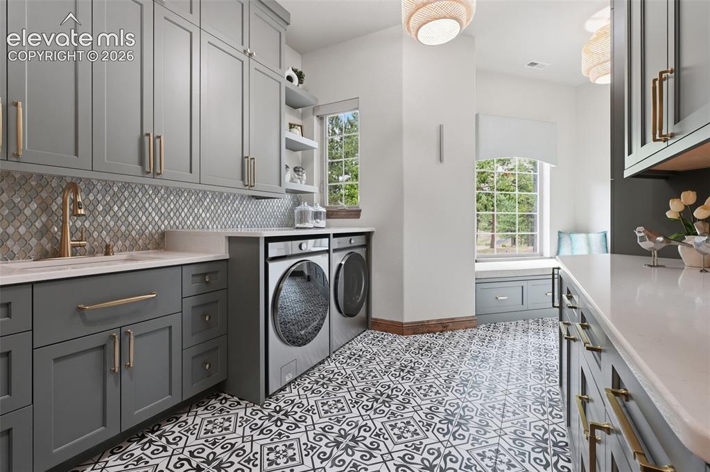 Image 25 of 50: A dream laundry room with quartz counters, deco tile, open shelving and win