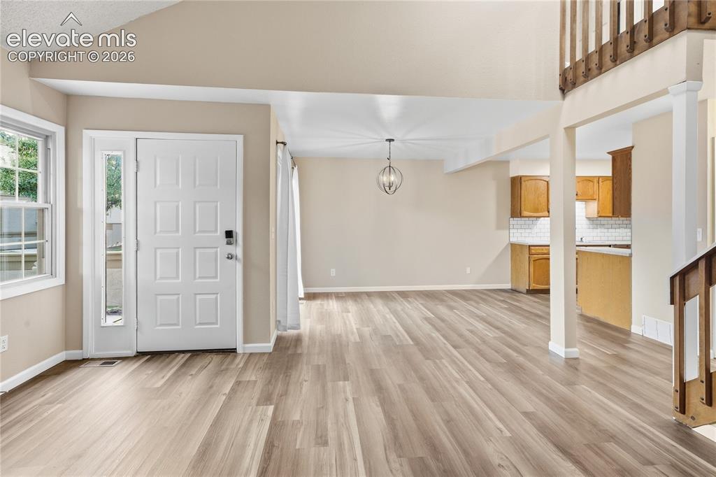 Image 10 of 35: Vaulted ceiling, wood-finish flooring, entry door with sidelight, open-conc