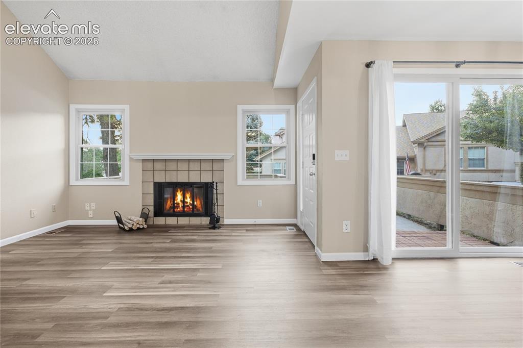 Image 11 of 35: Spacious interior featuring wood-finish flooring, a tile-surround fireplace