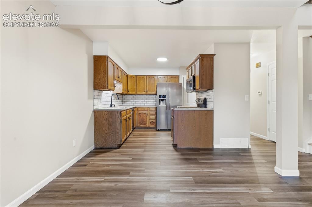 Image 13 of 35: Kitchen featuring wood-finish cabinetry, white subway tile backsplash, stai