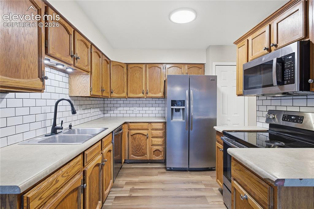 Image 14 of 35: Kitchen featuring wood cabinetry, subway tile backsplash, stainless steel a