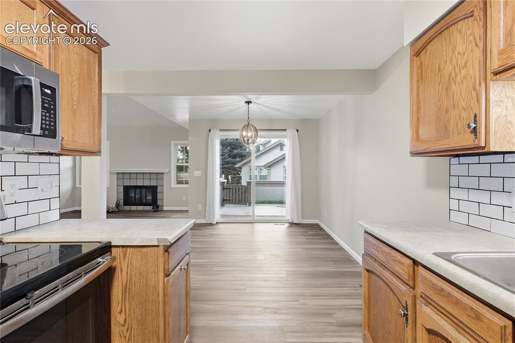Image 15 of 35: Wood-finish flooring throughout, stainless steel microwave, white subway ti