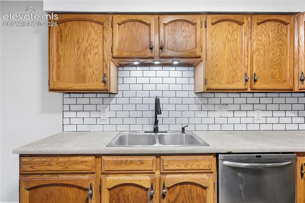 Image 16 of 35: Wood cabinetry, dual basin stainless steel sink, subway tile backsplash, ma