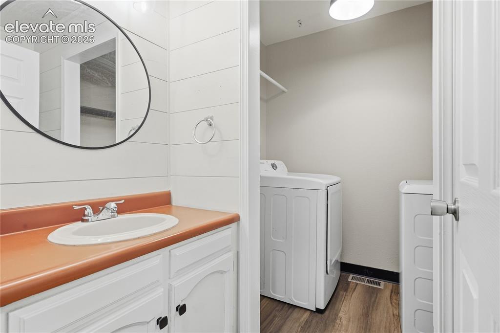 Image 17 of 35: White vanity with dark hardware, a orange countertop, and a circular mirror