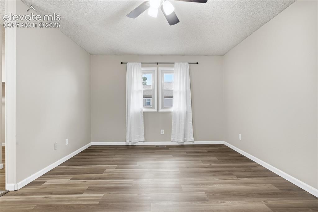 Image 18 of 35: Neutral wall color, wood-finish flooring, and a ceiling fan