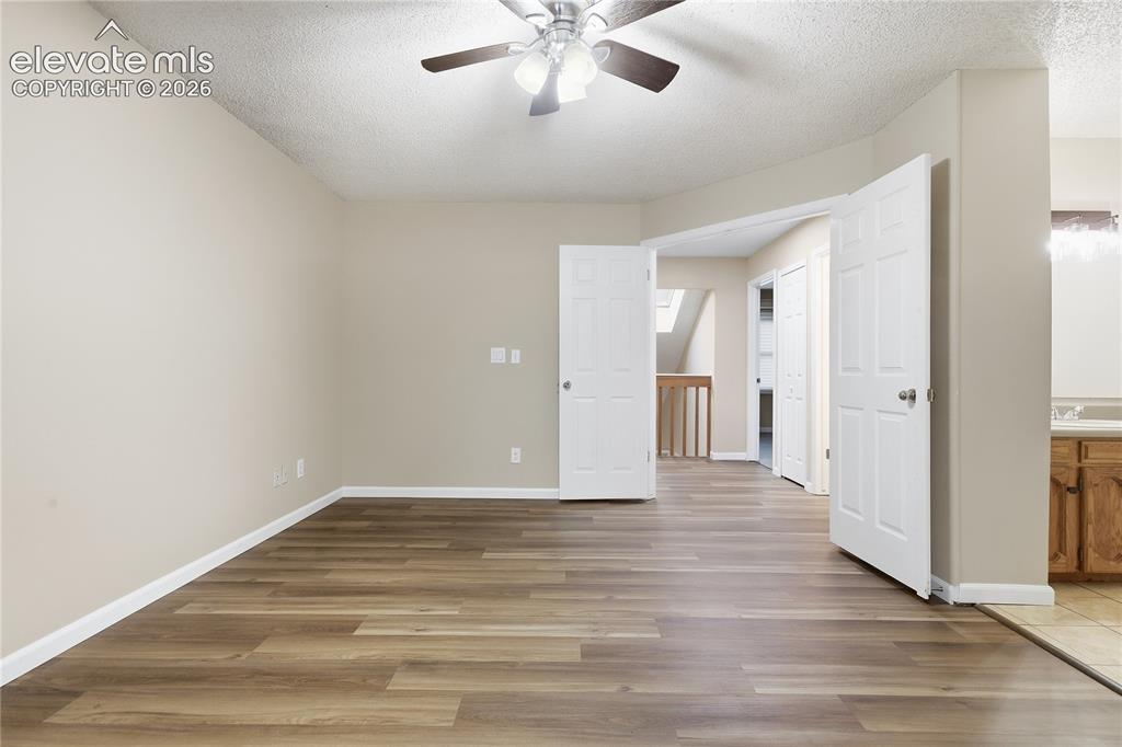 Image 19 of 35: Expansive room featuring wood-finish flooring, light-toned walls, and a cei