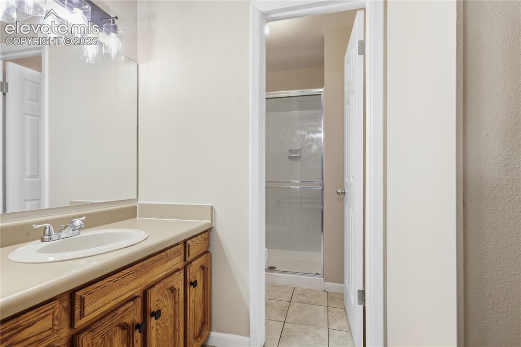 Image 22 of 35: Bathroom vanity with wood-finish cabinetry, integrated sink, and wall-mount