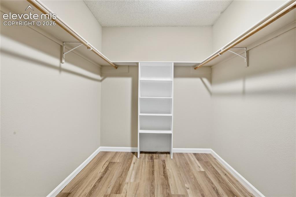 Image 23 of 35: Walk-in closet featuring wood-finish flooring, built-in shelving, and dual
