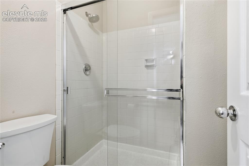 Image 24 of 35: Enclosed shower with clear glass surround, white tiled walls, and a chrome 