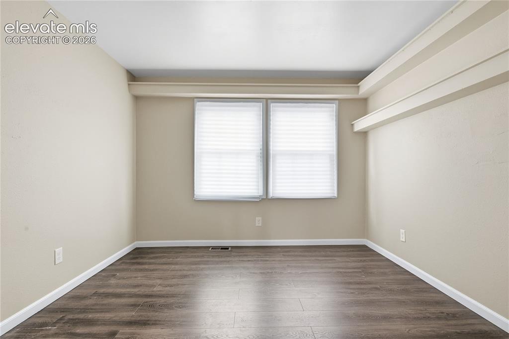 Image 26 of 35: Room featuring wood-finish flooring, neutral wall tones, and two windows