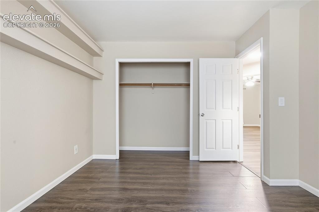 Image 27 of 35: Wood-finish flooring, neutral wall color, open closet with hanging rod, whi