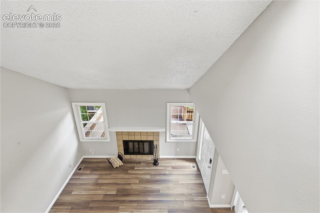 Image 28 of 35: Living area featuring wood-finish flooring, a fireplace with a brick surrou