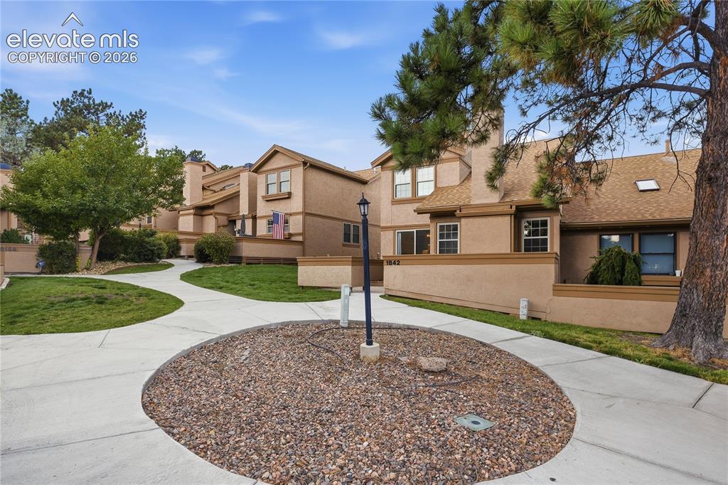 Image 3 of 35: Multi-level exterior with a tan stucco finish, brown trim, and a shingle ro