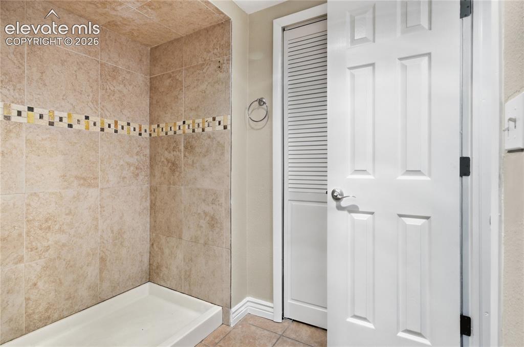 Image 33 of 35: Tiled shower surround with decorative mosaic accent band