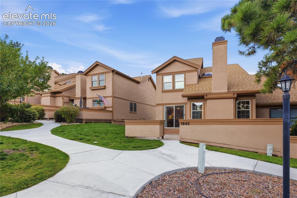 Image 4 of 35: Stucco exterior with a pitched shingle roof, featuring multiple windows, a 