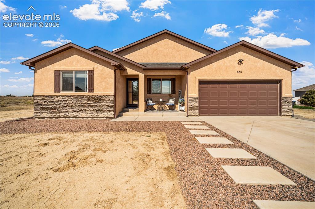 Image 1 of 50: Stucco exterior featuring a stone accent façade and a two-car garage