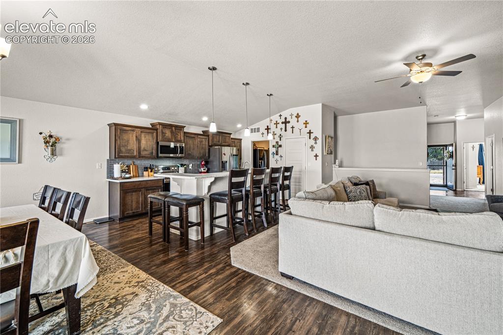 Image 12 of 50: Open-concept common area featuring wood-finish flooring, a kitchen with dar